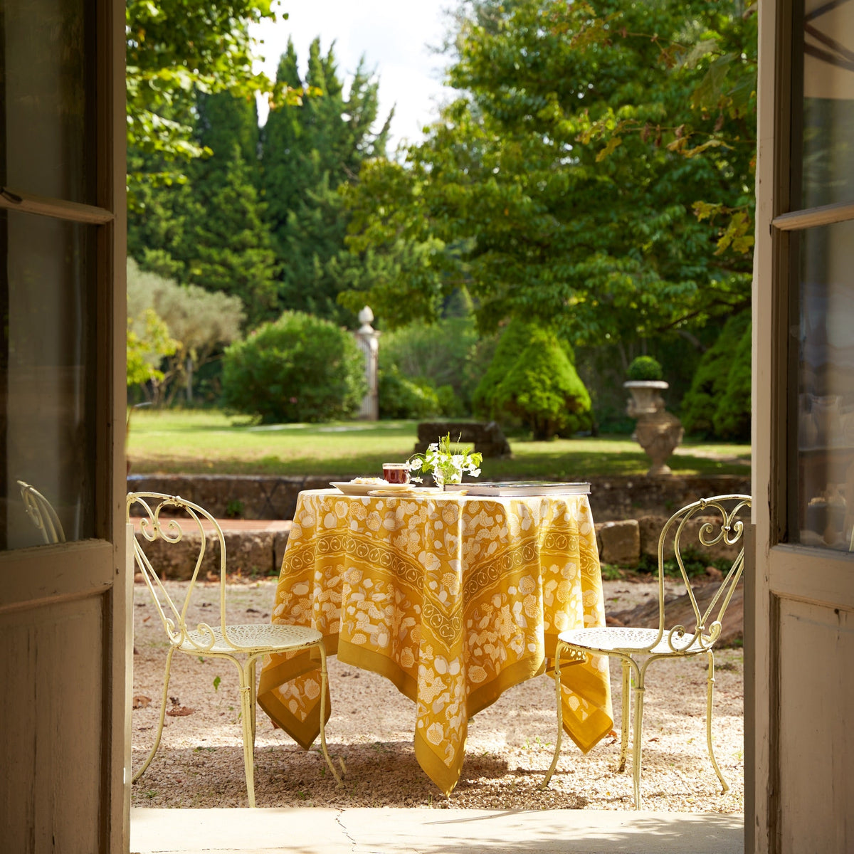 French Tablecloth Forest Harvest in Grey and Mustard displayed on a dining table in a garden setting