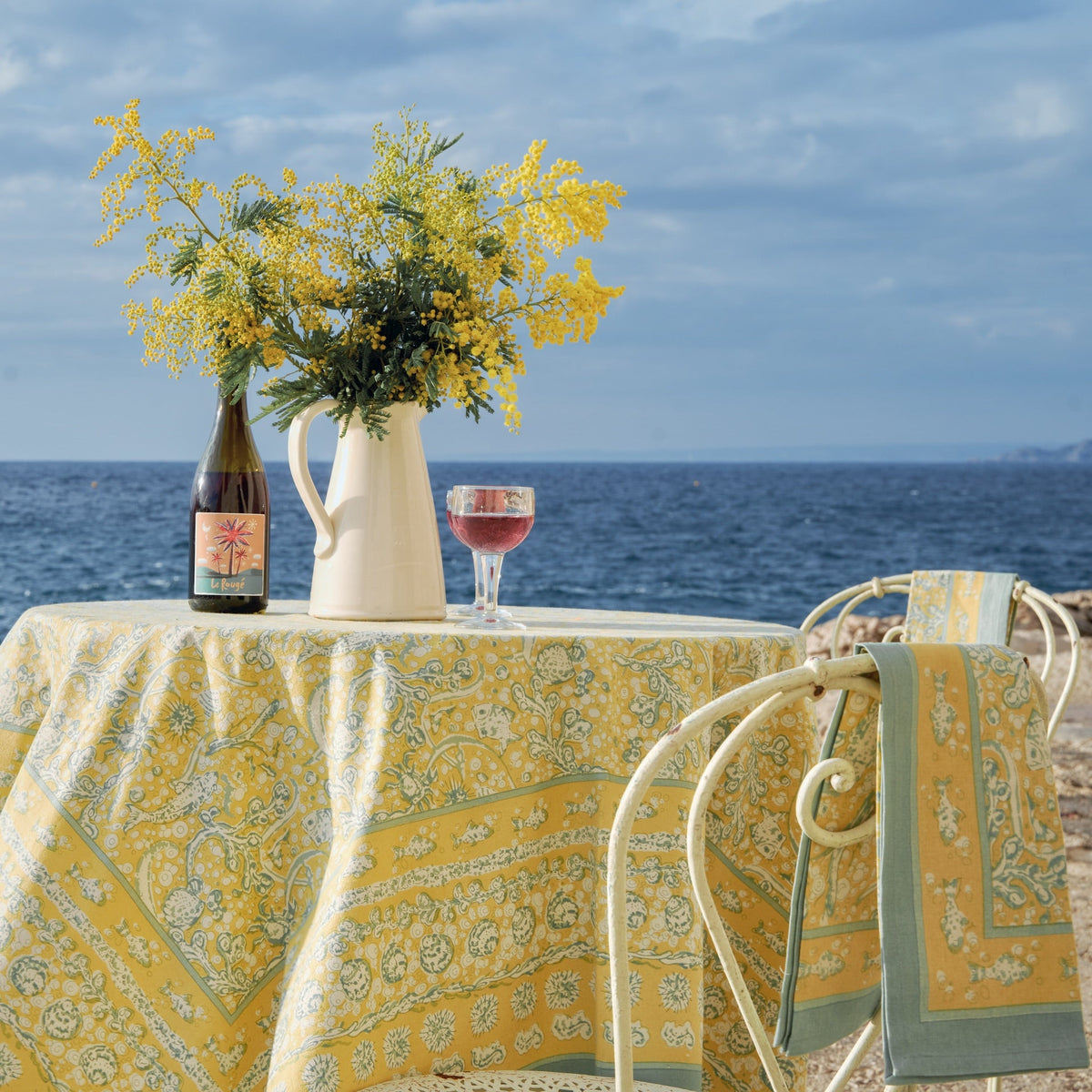 Front view of French Tablecloth La Mer Aqua and Citrine showcasing its patterned cotton fabric by the sea