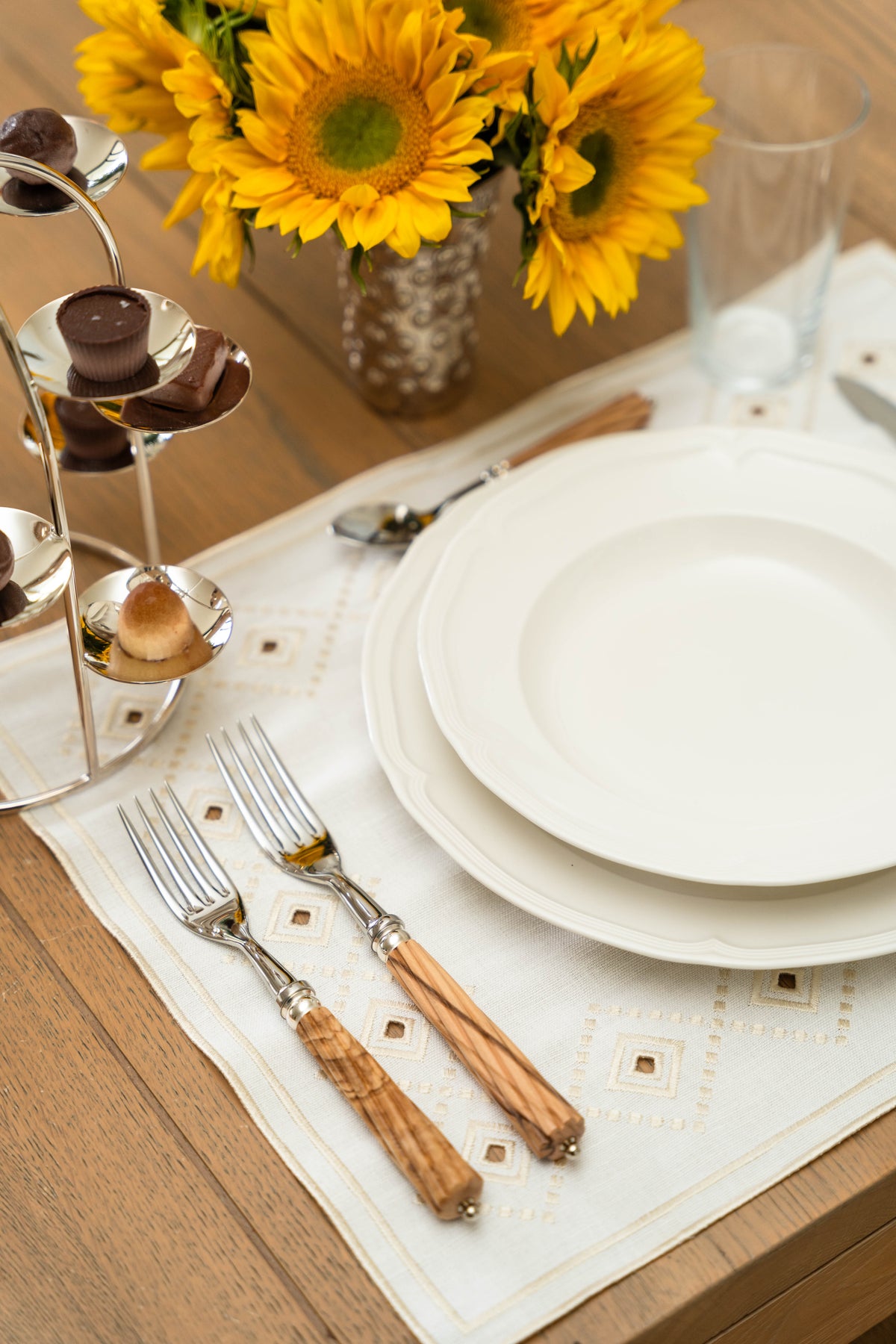Overhead view of Ojete Placemat in Ivory showcasing its subtle geometric pattern with tableware on a wooden table