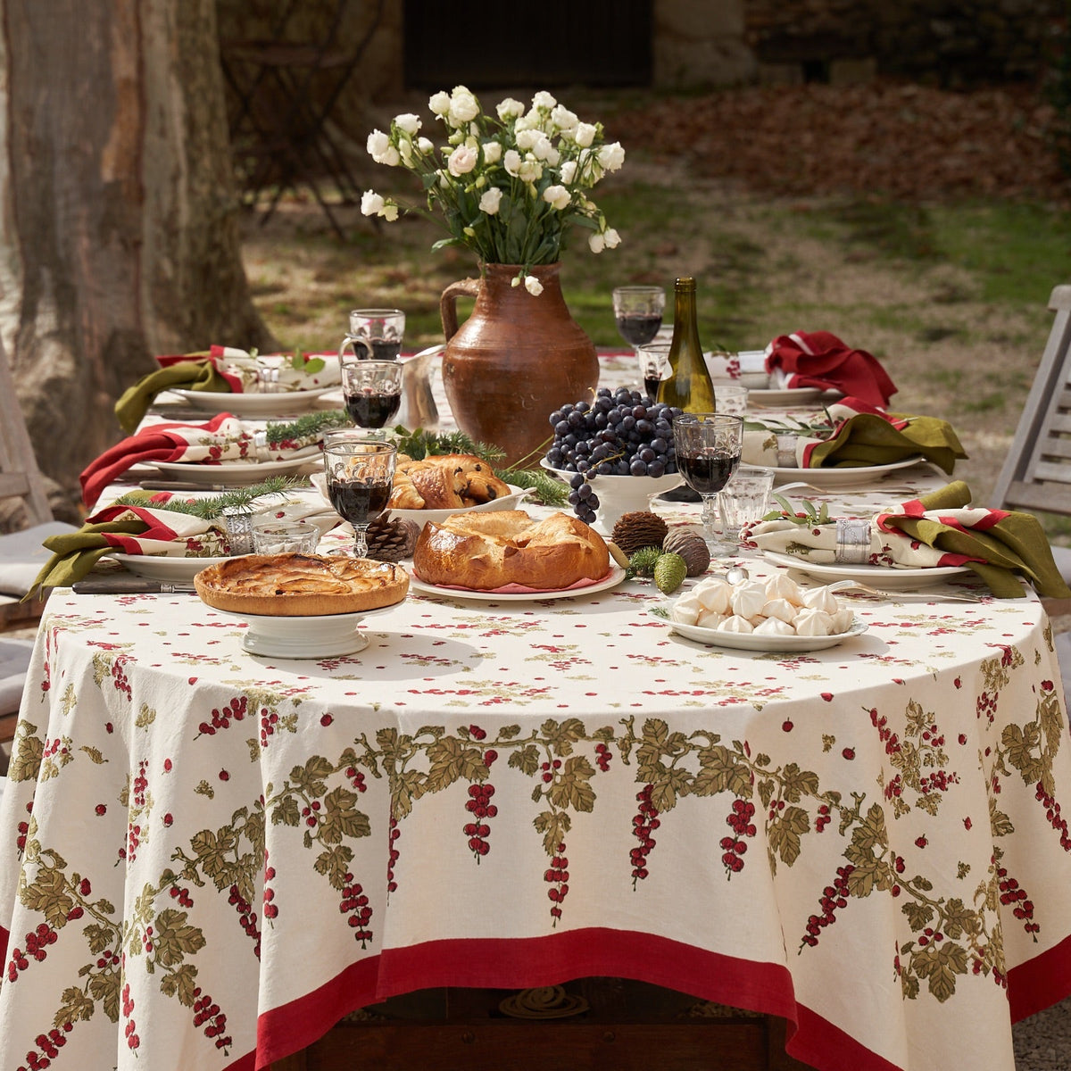 Front view of French Tablecloth Gooseberry showcasing mossy green and vermilion berry vines on ivory cotton in a tablescape