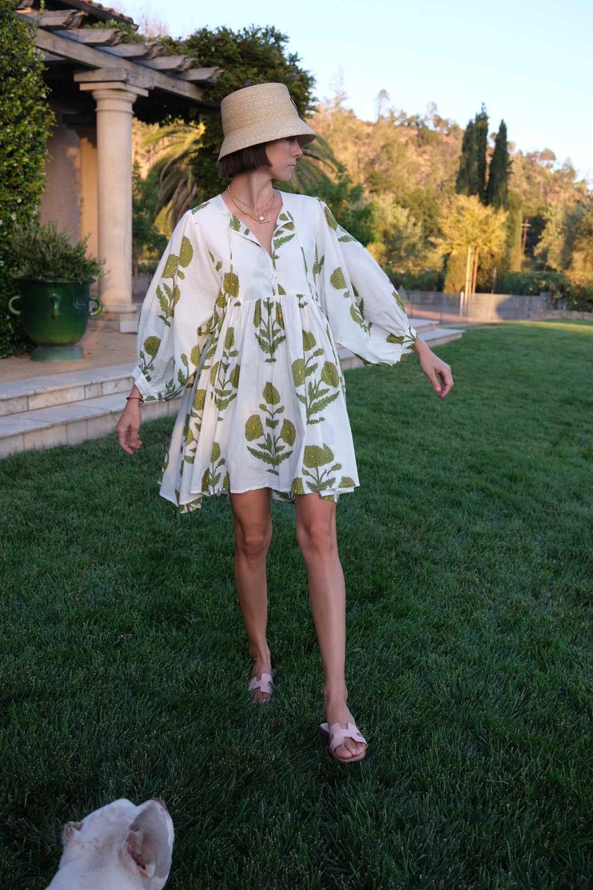 Front view of Taj Mini Dress Green Flower on model showing loose tiered silhouette and 3/4 balloon sleeves in garden