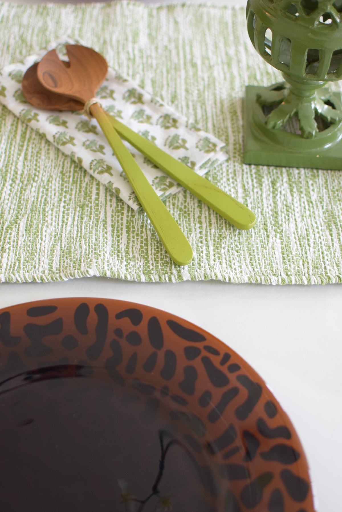 Close-up of Cheetah Charger, Set of 4 showcasing brown glass with black embossed abstract motif on a green table setting