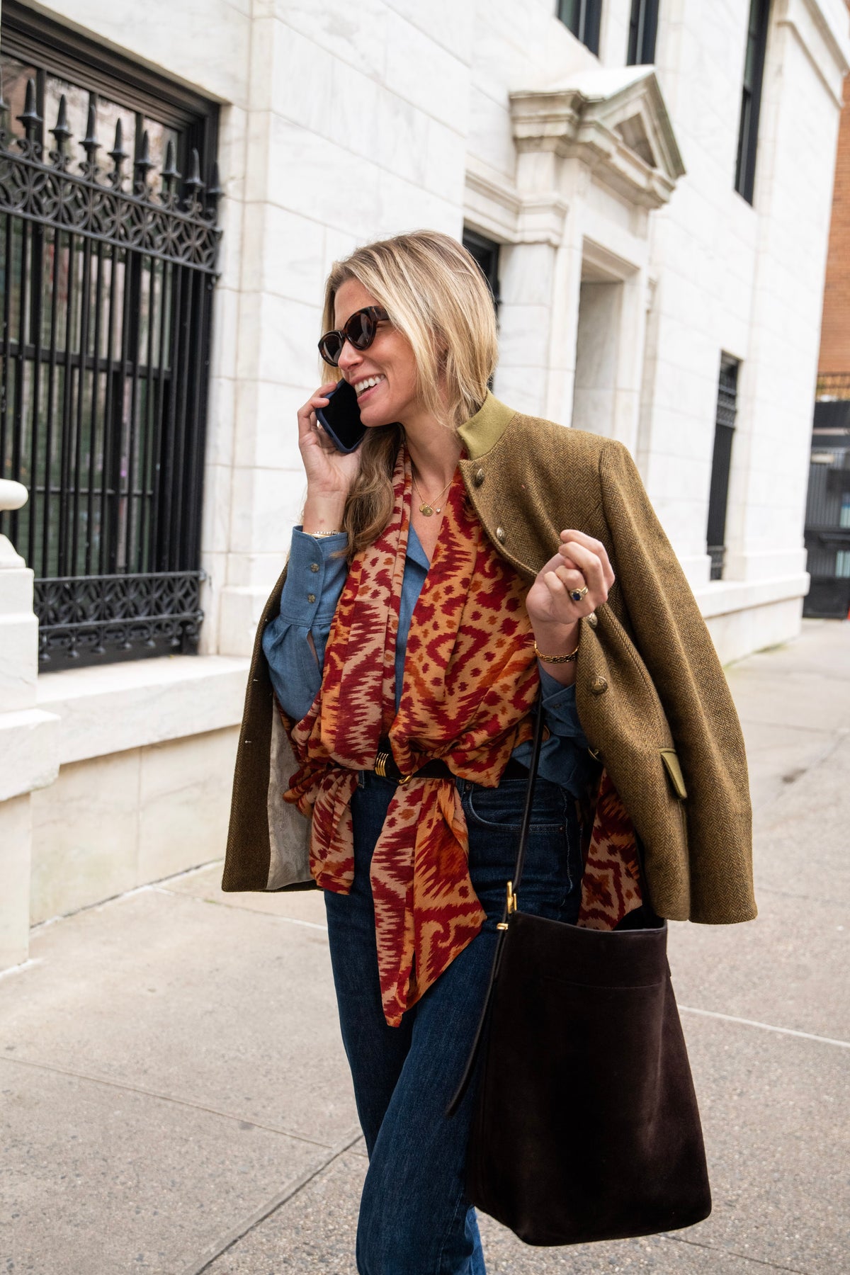 Woman wearing the Annabelle Pareo in red ikat as a scarf on a city sidewalk