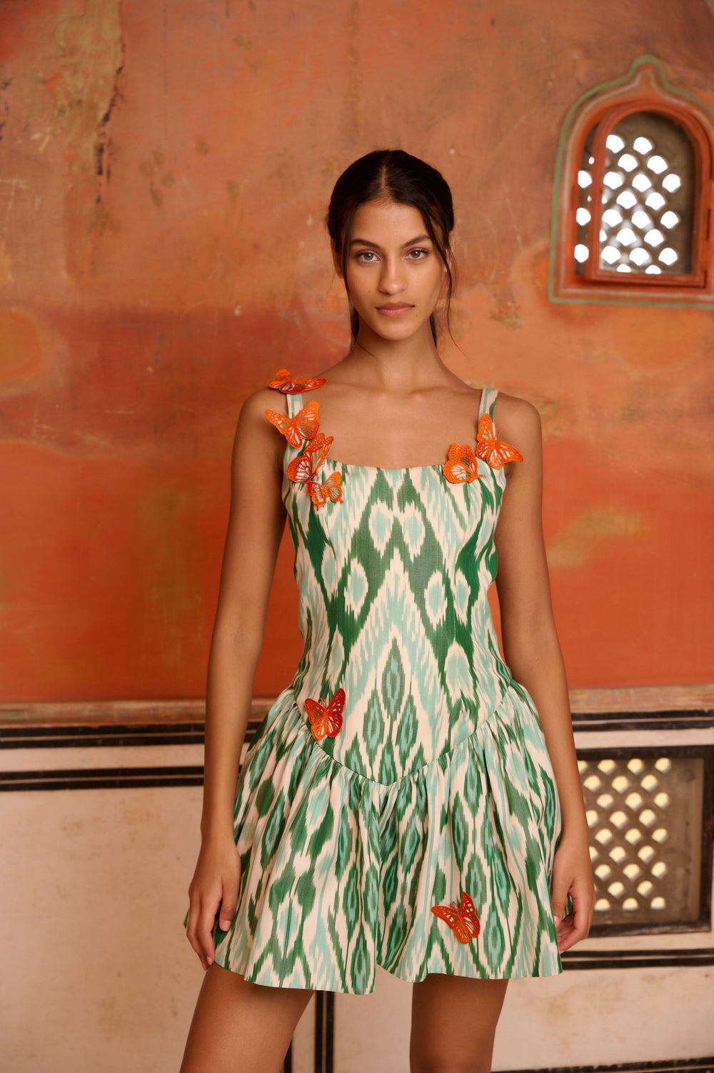 Front view of Mint Mirage Dress, mint-and-green ikat silk mini with corset waist and orange butterfly appliques