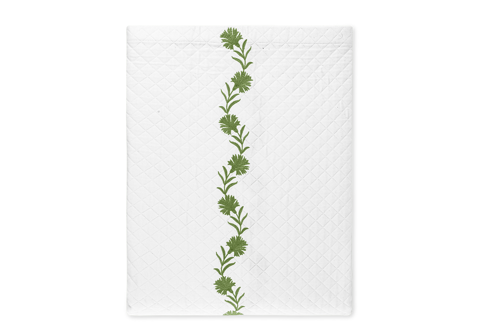 Flat lay of Daphne Matelasse coverlet with central green embroidered vine and quilted matelasse texture on black background