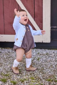 Little English traditional children's clothing company.  Short sleeve peter pan bubble in chocolate brown corduroy with wood button details for baby boys.  Paired with light blue cardigan with crochet abs on each side.