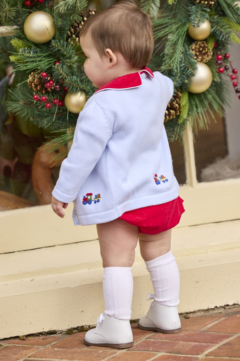 Little English classic children's clothing.  Red corduroy bubble with white contrast piping for baby boys for the holidays. Paired with light blue cardigan with holiday train embroidery