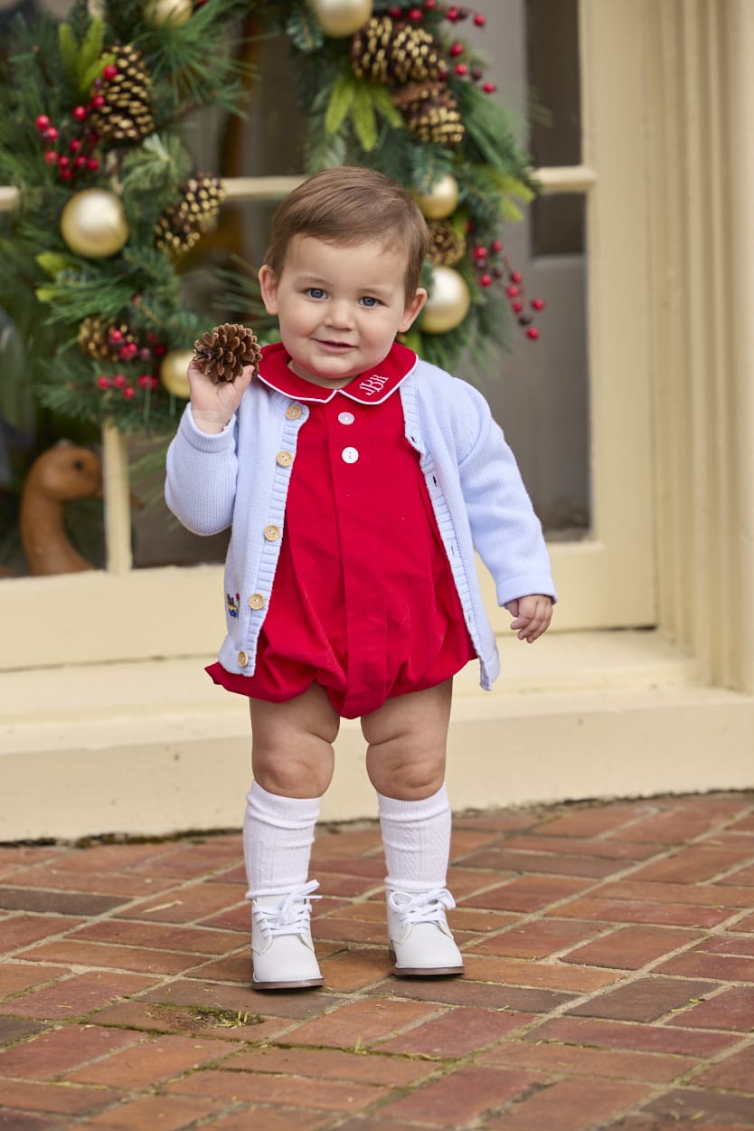 Little English classic children's clothing.  Red corduroy bubble with white contrast piping for baby boys for the holidays. Paired with light blue cardigan with holiday train embroidery