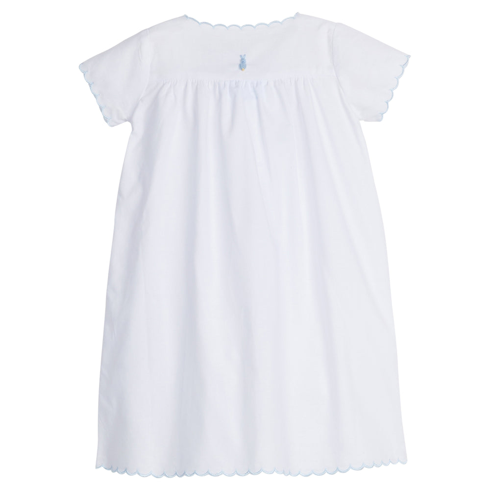 Back view of white baby day gown with blue bunny and carrot embroidery and scalloped blue trim on white background