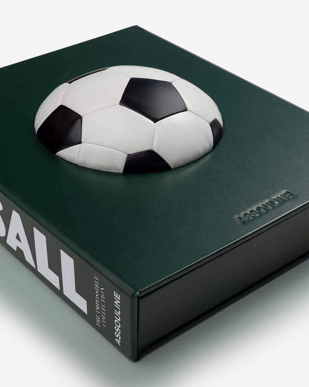 Football: The Impossible Collection by Assouline: angled overhead close-up of the slipcase lying flat; the three-dimensional black-and-white soccer ball rests on the dark forest green cover photographed from above; the lower spine shows ...BALL, THE IMPOSSIBLE COLLECTION, ASSOULINE in white; ASSOULINE embossed on the cover face at right; the green slipcase base and lid are visible