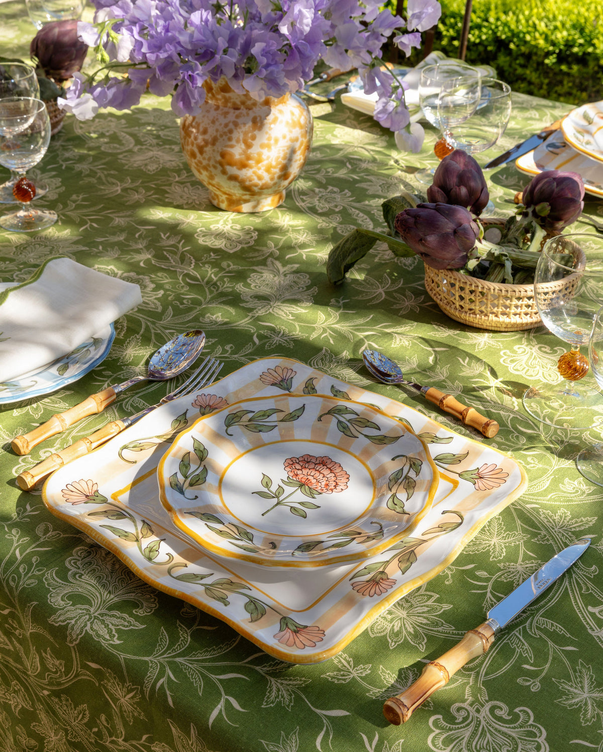 Angled view of DESTREE x Cabana yellow dessert plate showing hand-painted floral motif and square silhouette on a green patterned tablecloth