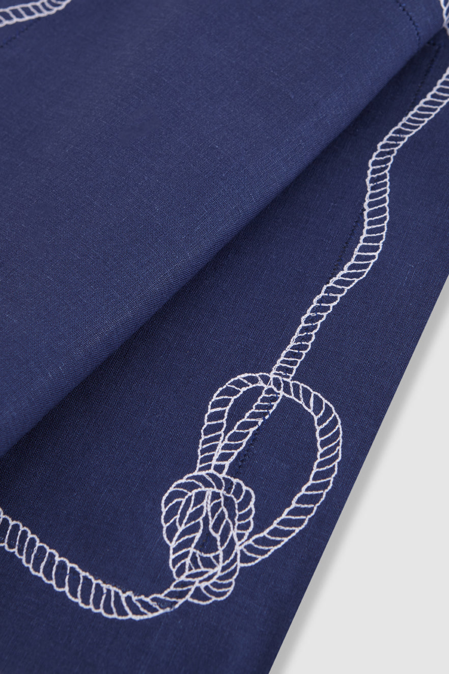 Close-up of Bowline linen placemat showcasing white embroidered rope border and bowline knot on navy background