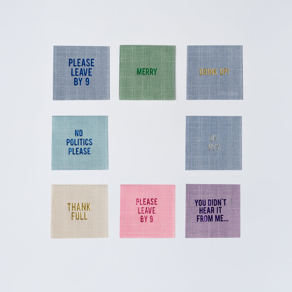 Top view of disposable linen-style cocktail napkins with the center pink napkin reading Please Leave By 9, nine colored napkin designs arranged on white background