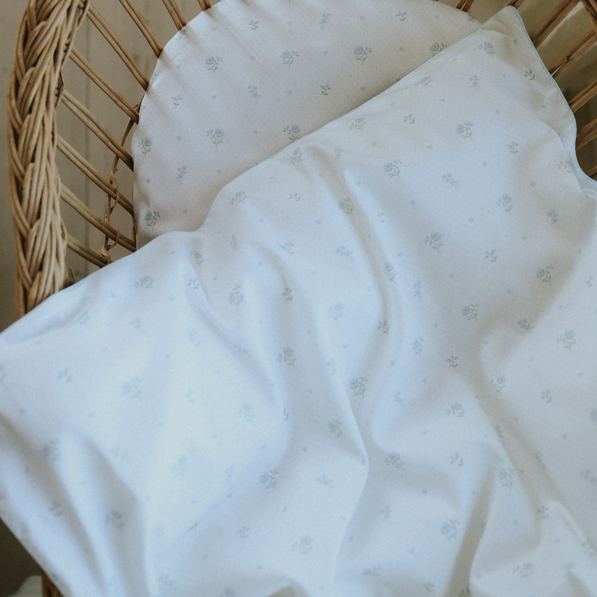 White baby blanket with subtle pattern draped over a wicker basket.