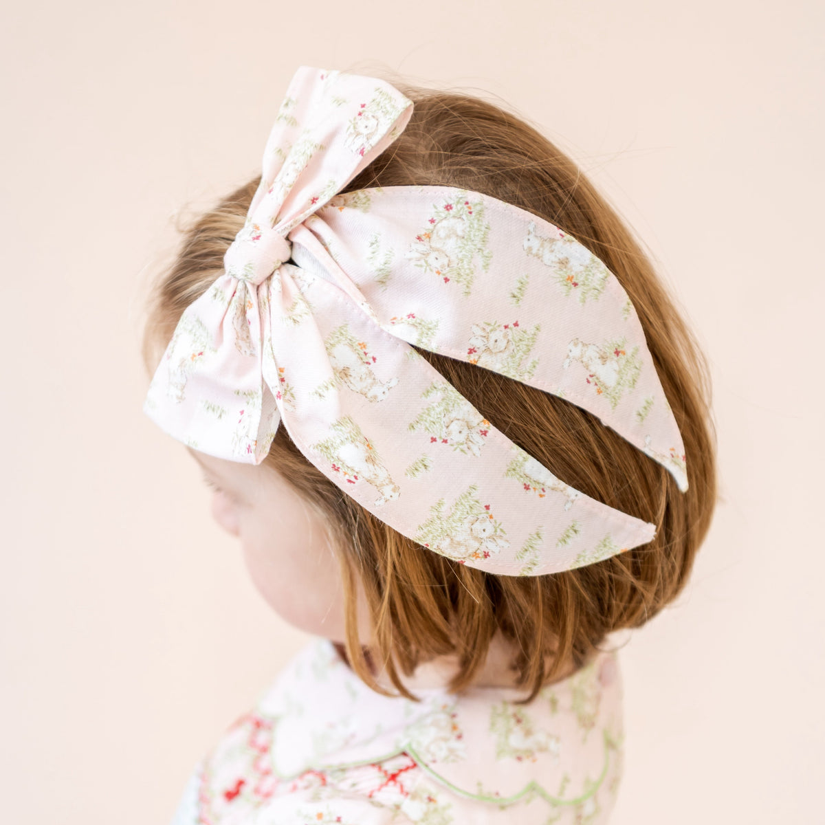 Close-up of Anna Bow in pink floral bunny print, worn on a child’s hair against a pale background