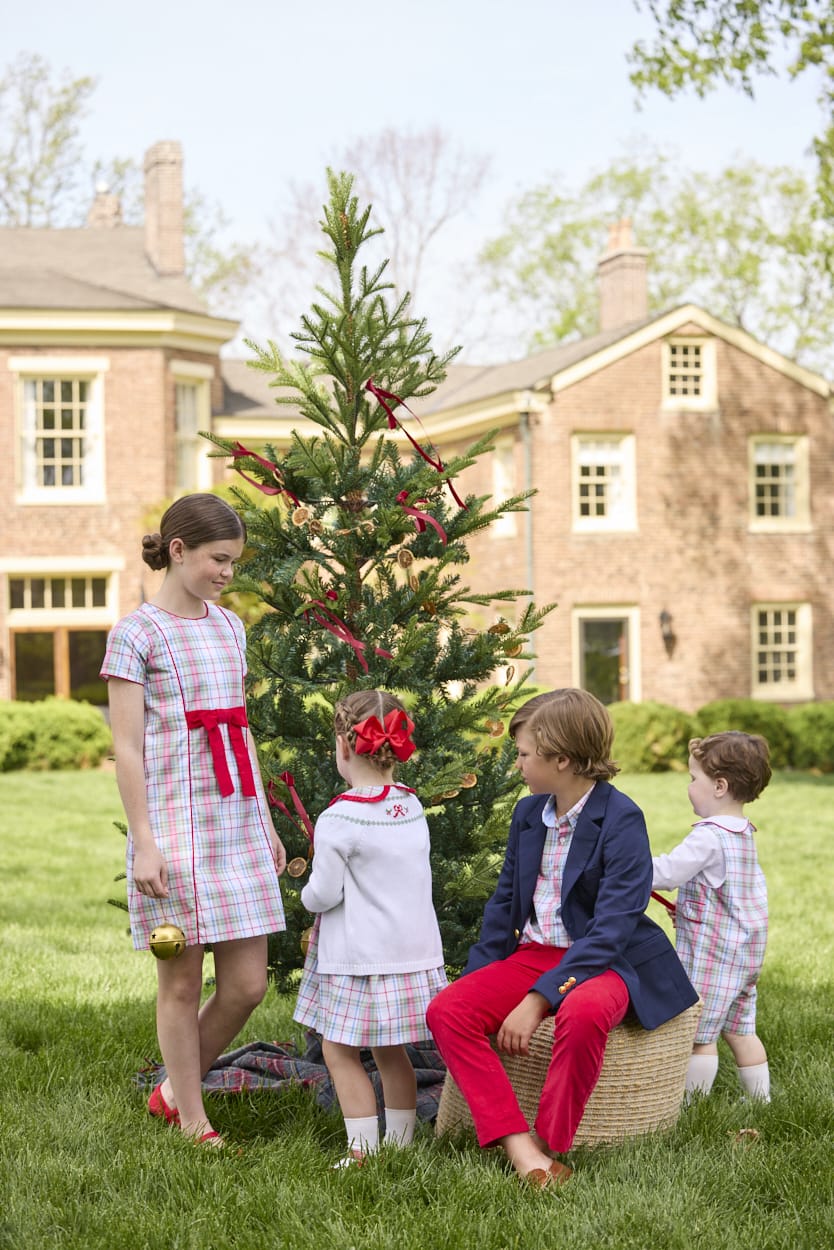 Little English classic children's clothing. Girls A-line Cora Dress in red and green plaid with red bow and red piping detail for the holidays.  Boys Douglas Plaid button down shirt with red corduroy pants and navy wool blazer. Toddler girls Eleanor Dress - Douglas Plaid with ruffled peter pan collar and tie sash in back paired with white Holiday Bow Fair Isle Cardigan.  Toddler boys Douglas Plaid Button Tab John John Set