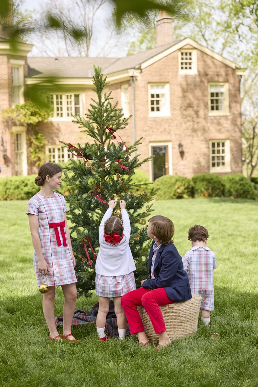 Little English classic children's clothing. Girls A-line Cora Dress in red and green plaid with red bow and red piping detail for the holidays.  Boys Douglas Plaid button down shirt with red corduroy pants and navy wool blazer. Toddler girls Eleanor Dress - Douglas Plaid with ruffled peter pan collar and tie sash in back paired with white Holiday Bow Fair Isle Cardigan.  Toddler boys Douglas Plaid Button Tab John John Set
