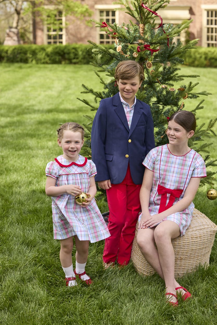 Little English classic children's clothing. Girls A-line Cora Dress in red and green plaid with red bow and red piping detail for the holidays.  Boys Douglas Plaid button down shirt with red corduroy pants and navy wool blazer. Toddler girls Eleanor Dress - Douglas Plaid with ruffled peter pan collar and tie sash in back. 