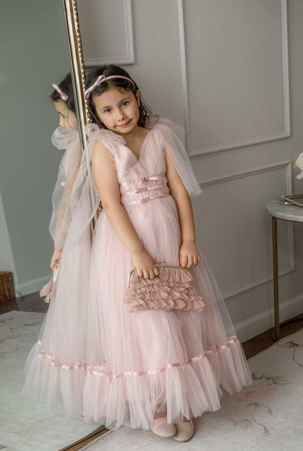 Girl wearing Camila Light Pink Tulle Gown with flutter tulle sleeves and tiered skirt, styled for flower girl or special occasion.