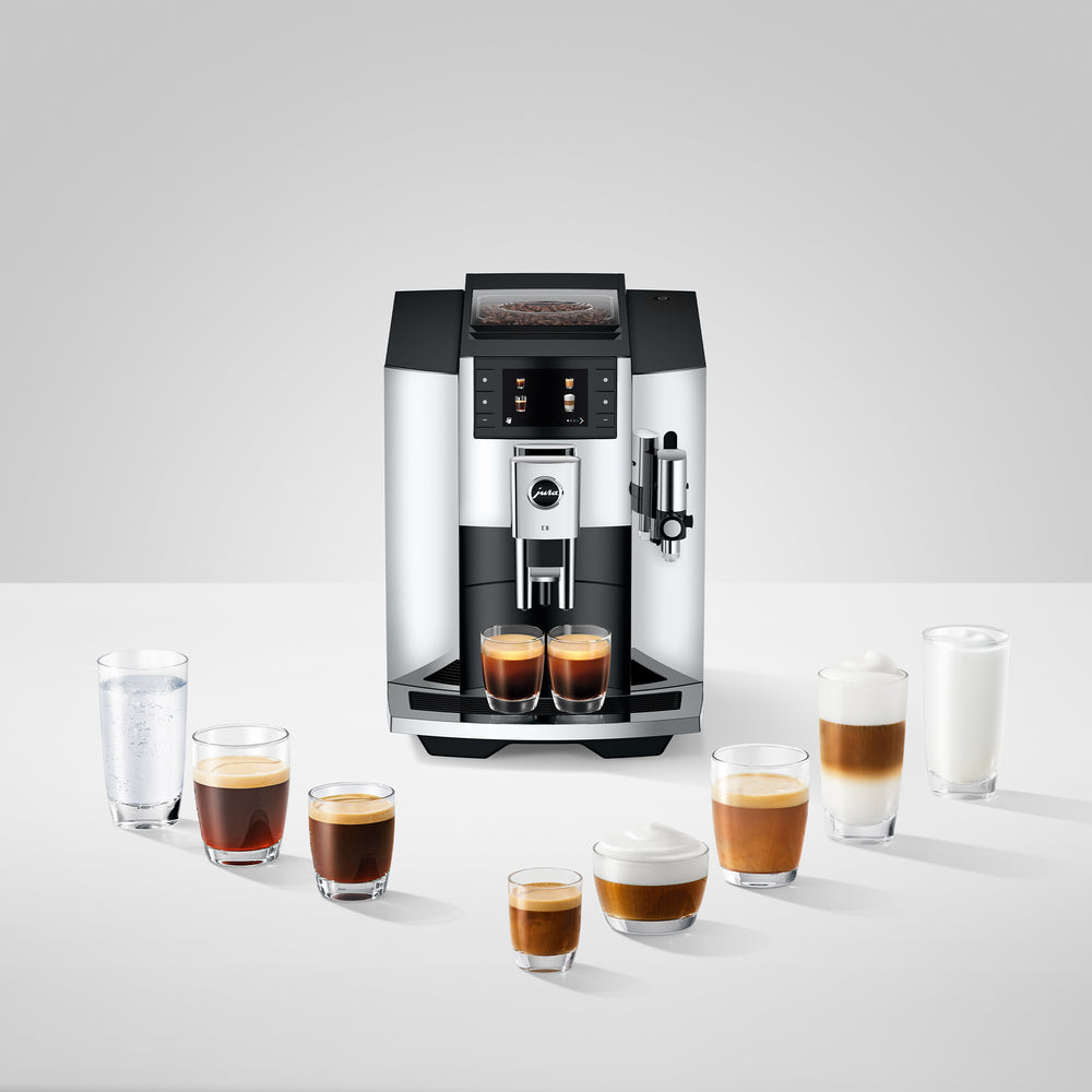 Front view of E8 chrome coffee machine showing touchscreen, double spout pouring two espressos and milk frother on white background