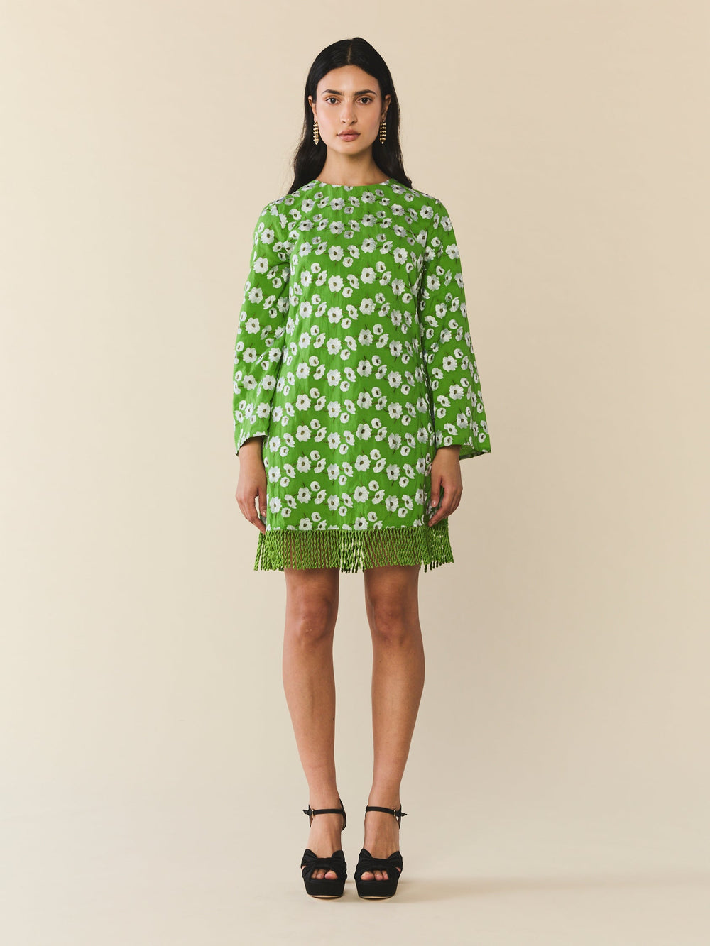 Front view of Tillie Dress in Magnolia Green embroidery showing mini shift silhouette, long bell sleeves, and fringe hem on beige background