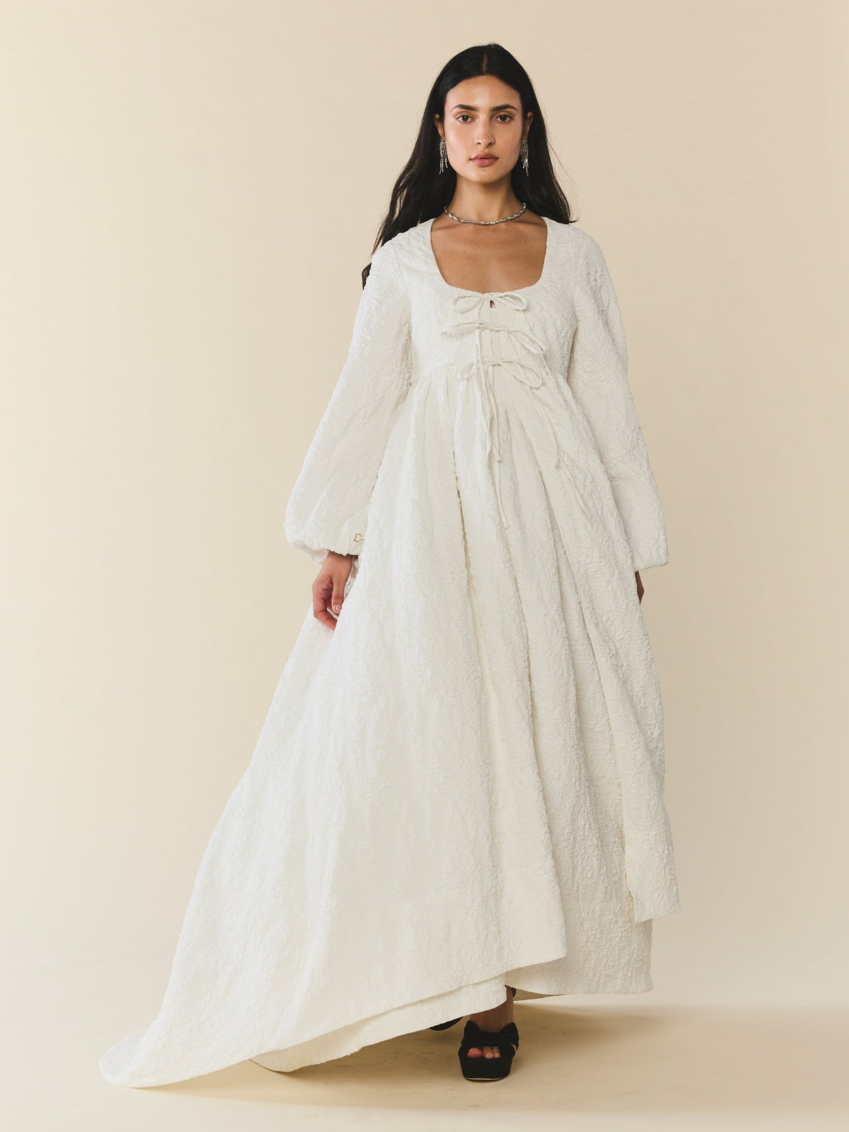 Front view of Sweet Pea Cape in Chapel White Floral with square tie-front neckline, voluminous long sleeves, quilted floral texture, and soft train