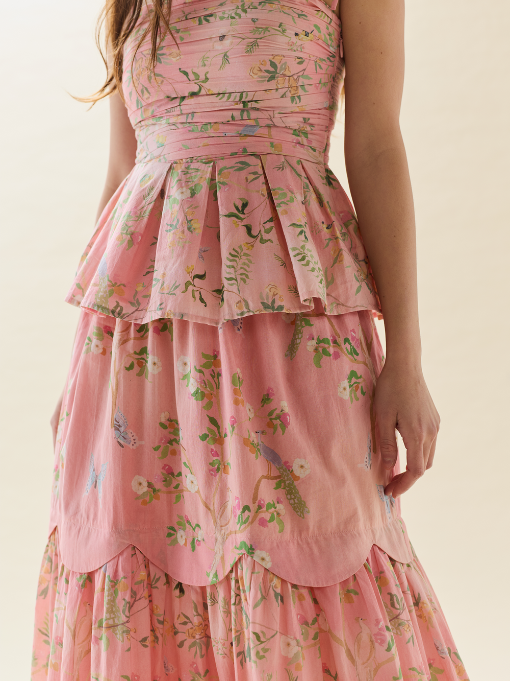 Front close-up of Erin Skirt showcasing scalloped yoke and tiered gathered midi silhouette in pink Peony Peacock print on beige background