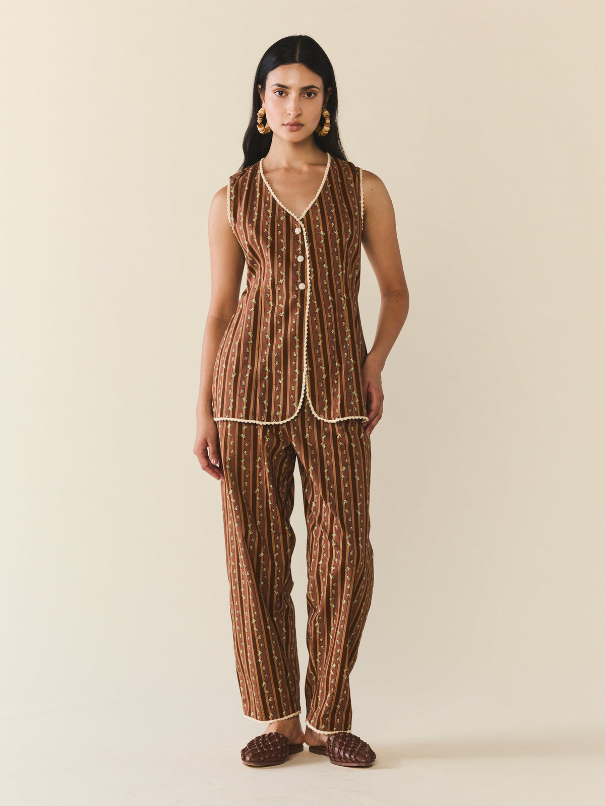 Front view of Alexa Top sleeveless tailored vest with V-neck and button-front in chocolate stripes with small floral print and cream trim on beige background