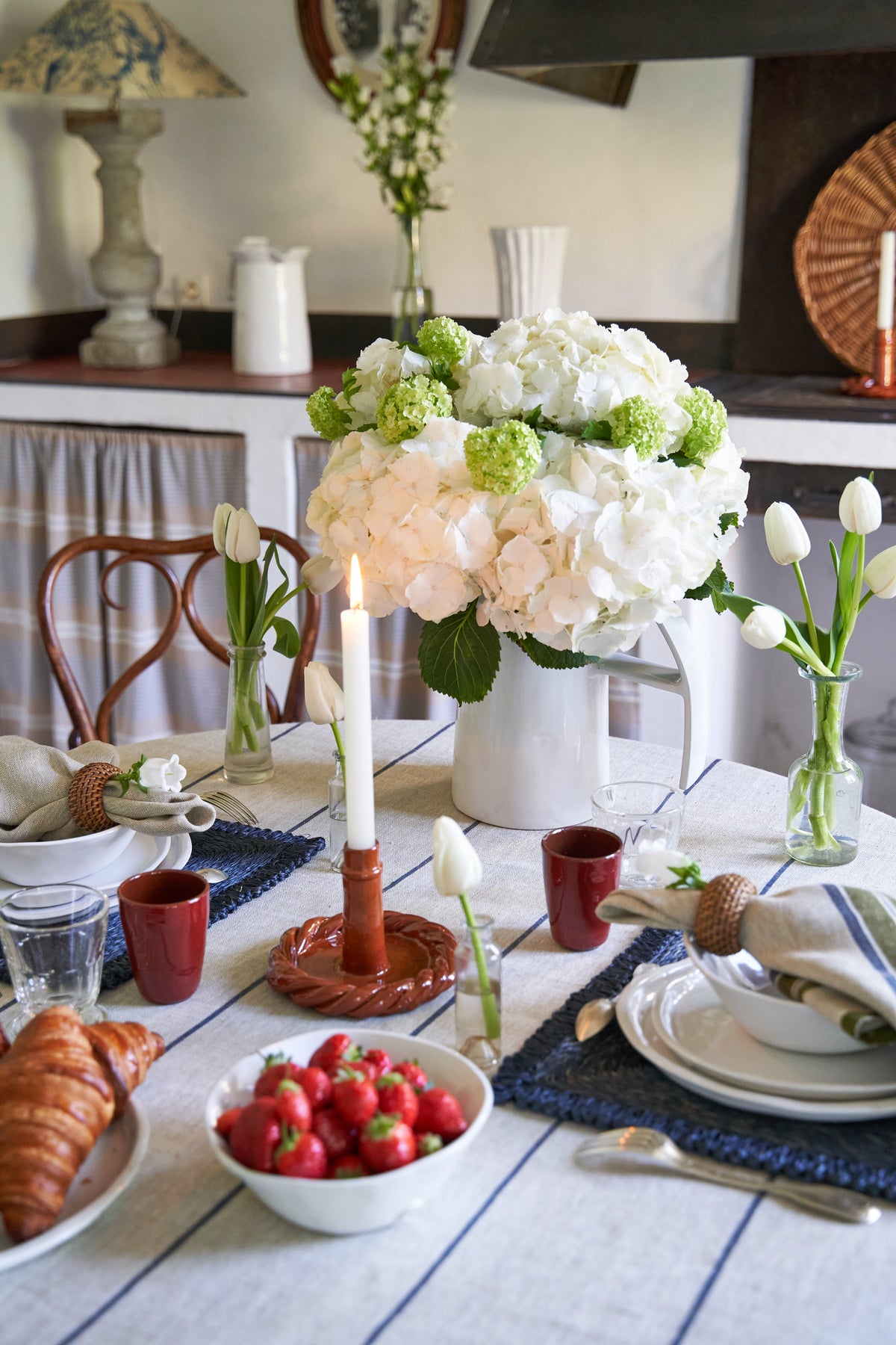 Ivory and blue striped tablecloth styled on a dining table with flowers, dishes, and candles