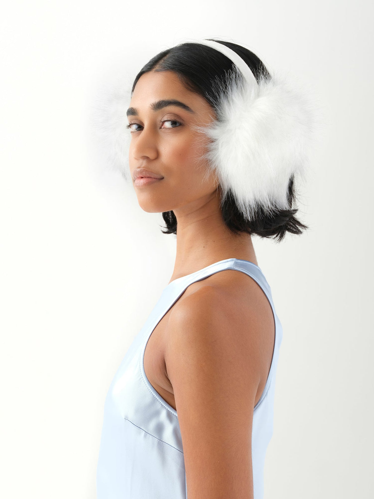 A model in three-quarter profile wearing white faux fur earmuffs.