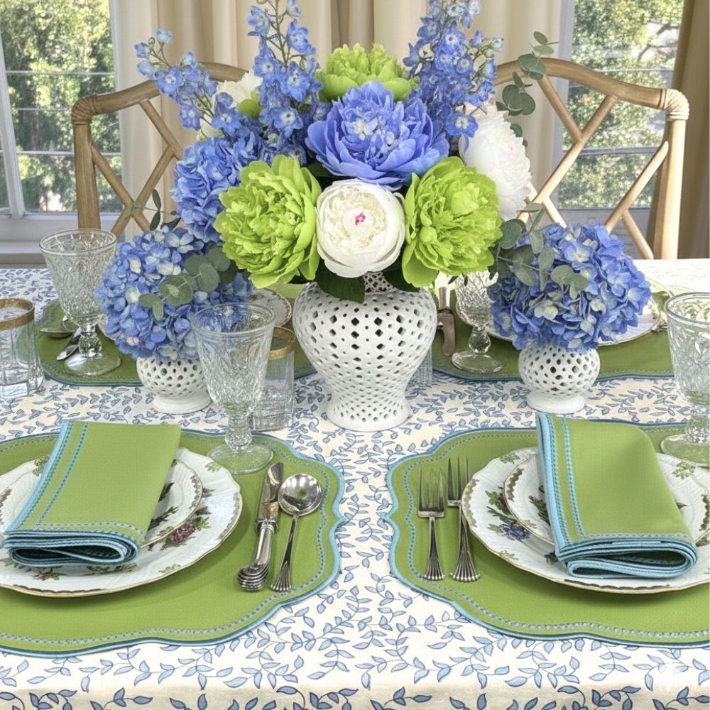 Elegant table setting with blue and green floral arrangement, white plates, and silverware.