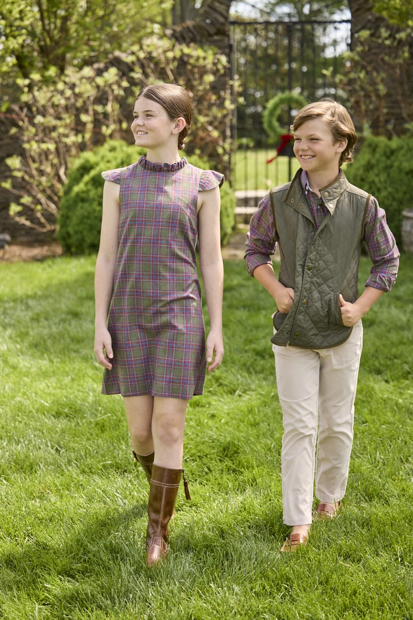 Little English traditional children's clothing. Olive and maroon Thornhill Plaid column dress with capped sleeves, ruffled neckline, and fixed bow in back for older girls for the holidays.  Boys Button Down Shirt in Thornhill Plaid with Classic Quilted Vest in Olive layered over top. Paired with Classic Pant in tan Stone Corduroy.