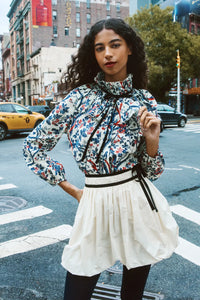 The Eloise Blouse is framed by a pleated yoke, a high ruffled collar, and tied with velvet ribbon. 