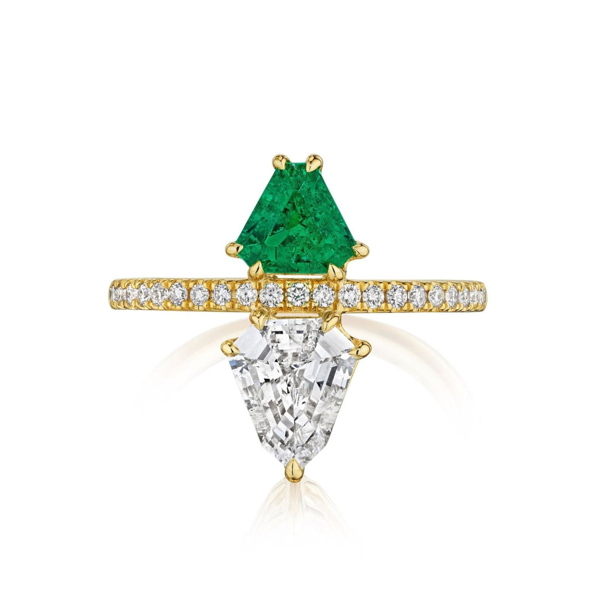 The Emerald and Diamond Double Shield Ring in Yellow Gold showcases a triangular green emerald and a trapezoid white diamond, separated by a yellow gold band adorned with small round diamonds.