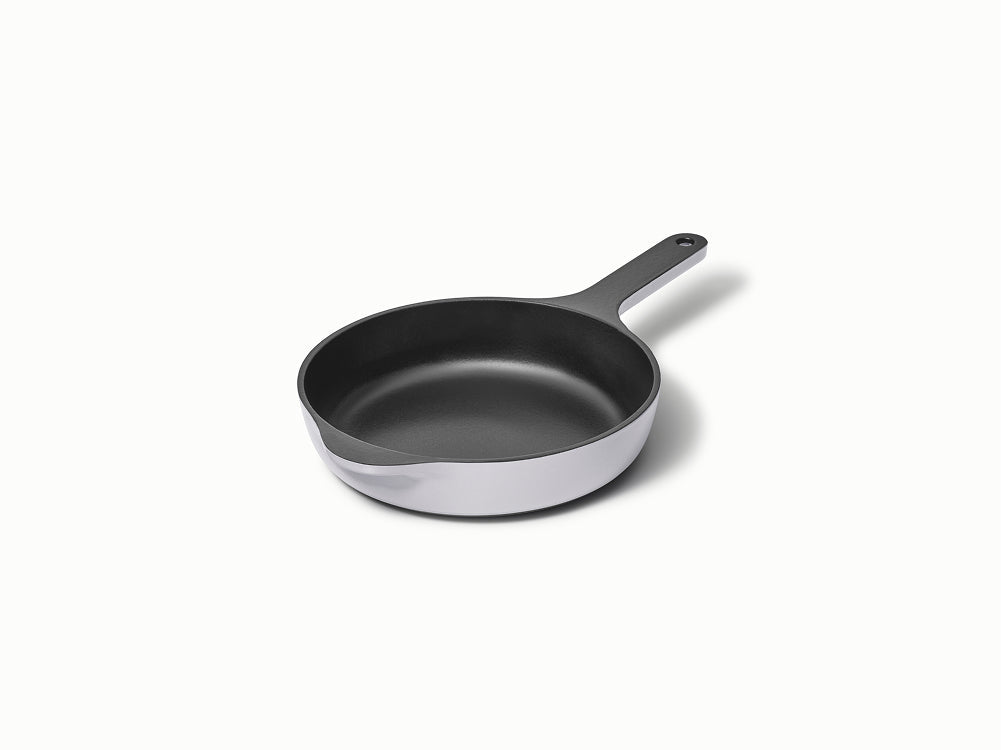 Angled view of 8-inch enameled cast iron skillet with black interior and light gray exterior on white background