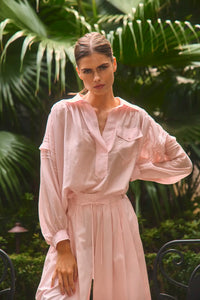 The Evangeline Shirt in Pink Sand paired with the matching Whisper Pant with palm leaves background.