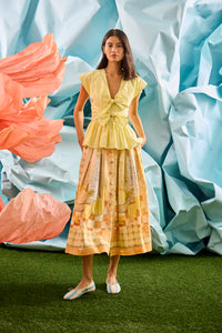 Eva Skirt in Still Life Symphony paired with Everly Top in Lemon Meringue, in front of colorful wall.