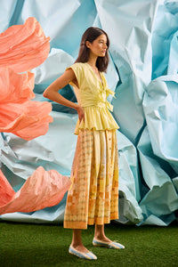 Eva Skirt in Still Life Symphony paired with Everly Top in Lemon Meringue, in front of colorful wall.
