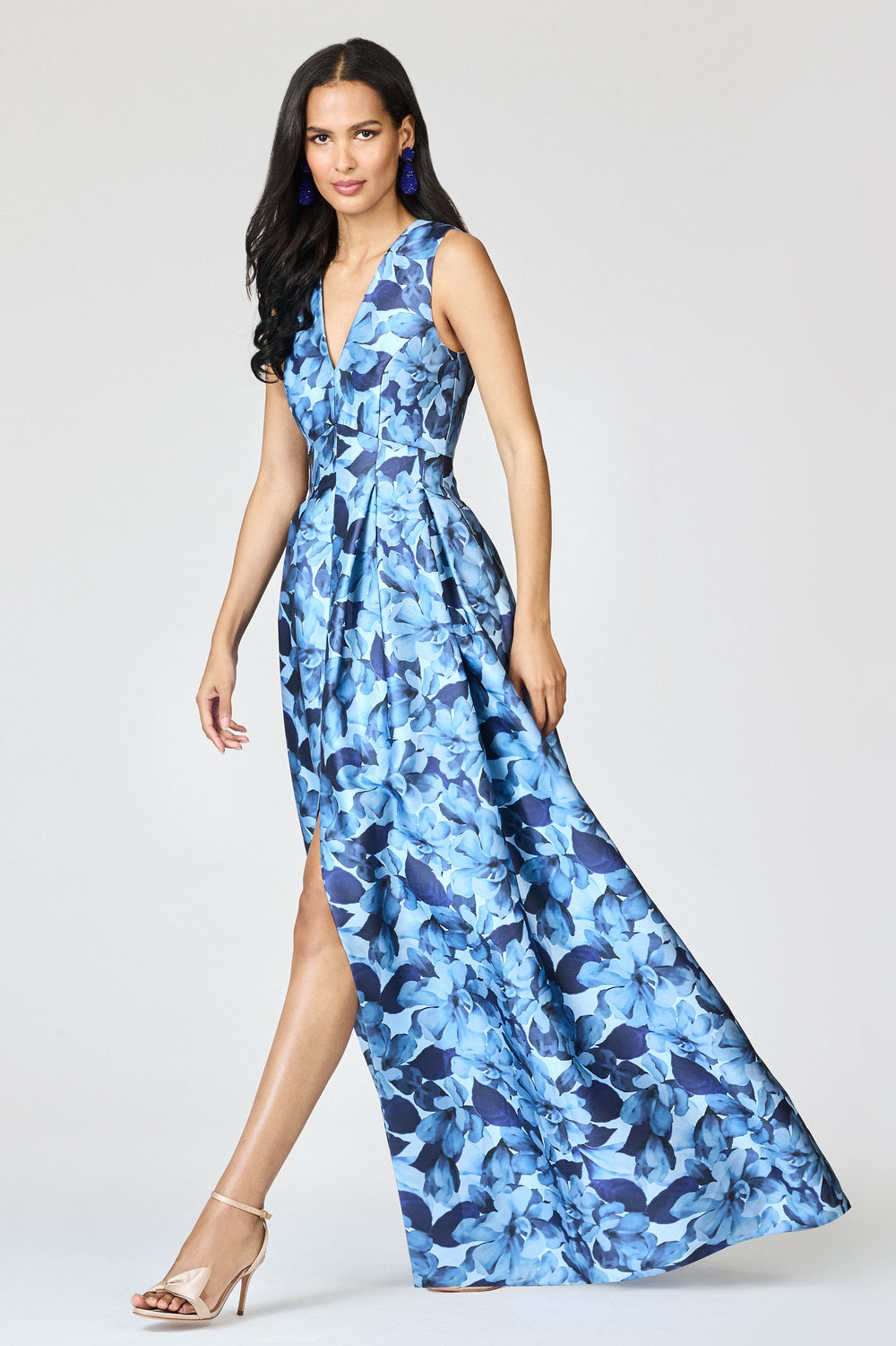 Three-quarter view of Brooke Gown in Frosted Magnolias on model, V-neck, peaked waist, box-pleated full skirt with front slit, light gray background