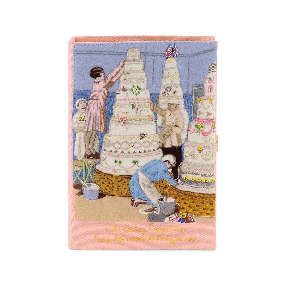 Front view of Cake Baking Competition book clutch showcasing hand-embroidered bakers and tiered cakes with pink trim on white background