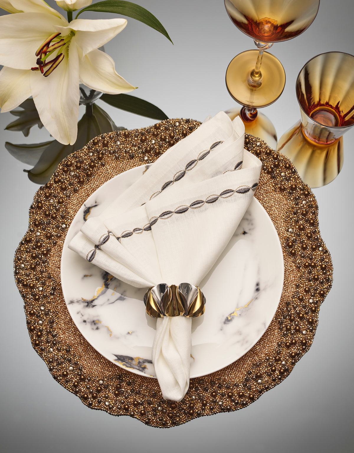 Top view of Swag Napkin in White, Gunmetal & Silver, Set of 4 showcasing marquee shapes outlined in silver thread on a table