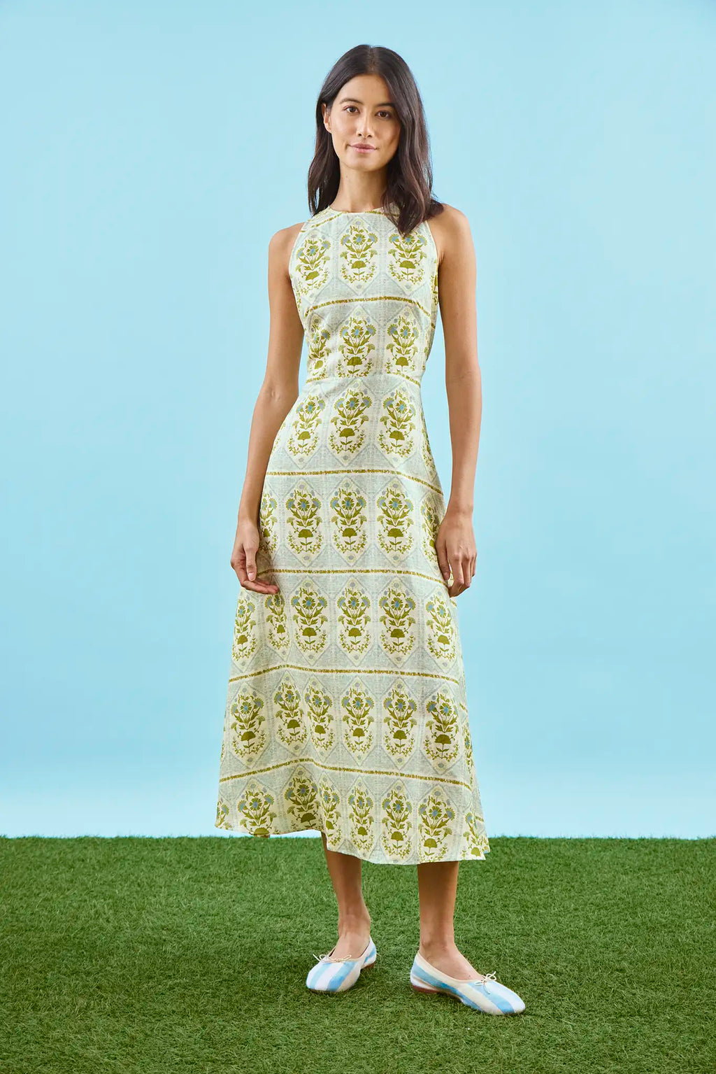 Faith Dress in Green Trellis modeled in front of blue wall.