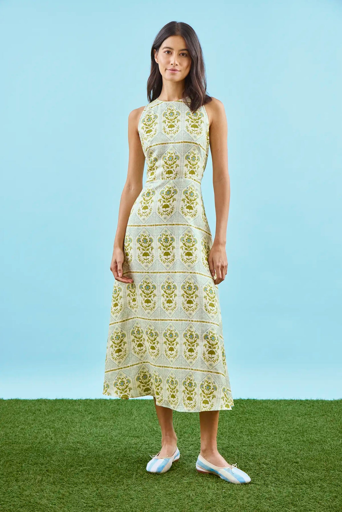 Faith Dress in Green Trellis modeled in front of blue wall.