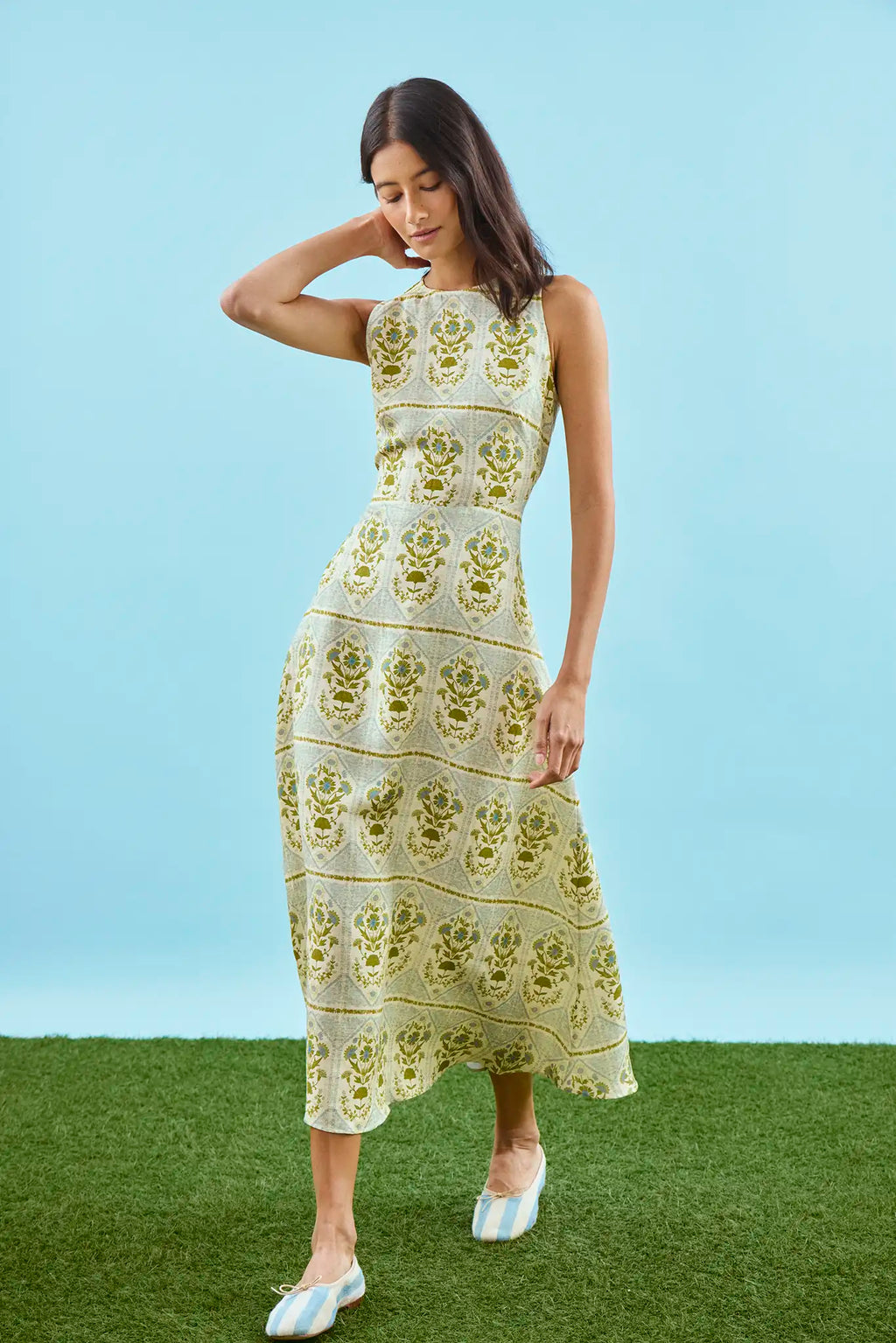 Faith Dress in Green Trellis modeled in front of blue wall.