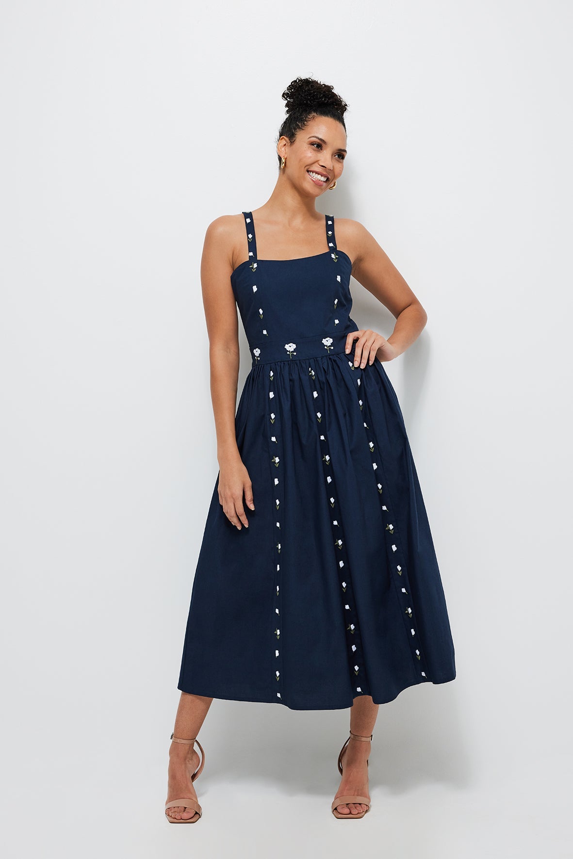 Front view of Hulya midi dress in indigo blue with square neckline, embroidered floral trim and full skirt on gray background