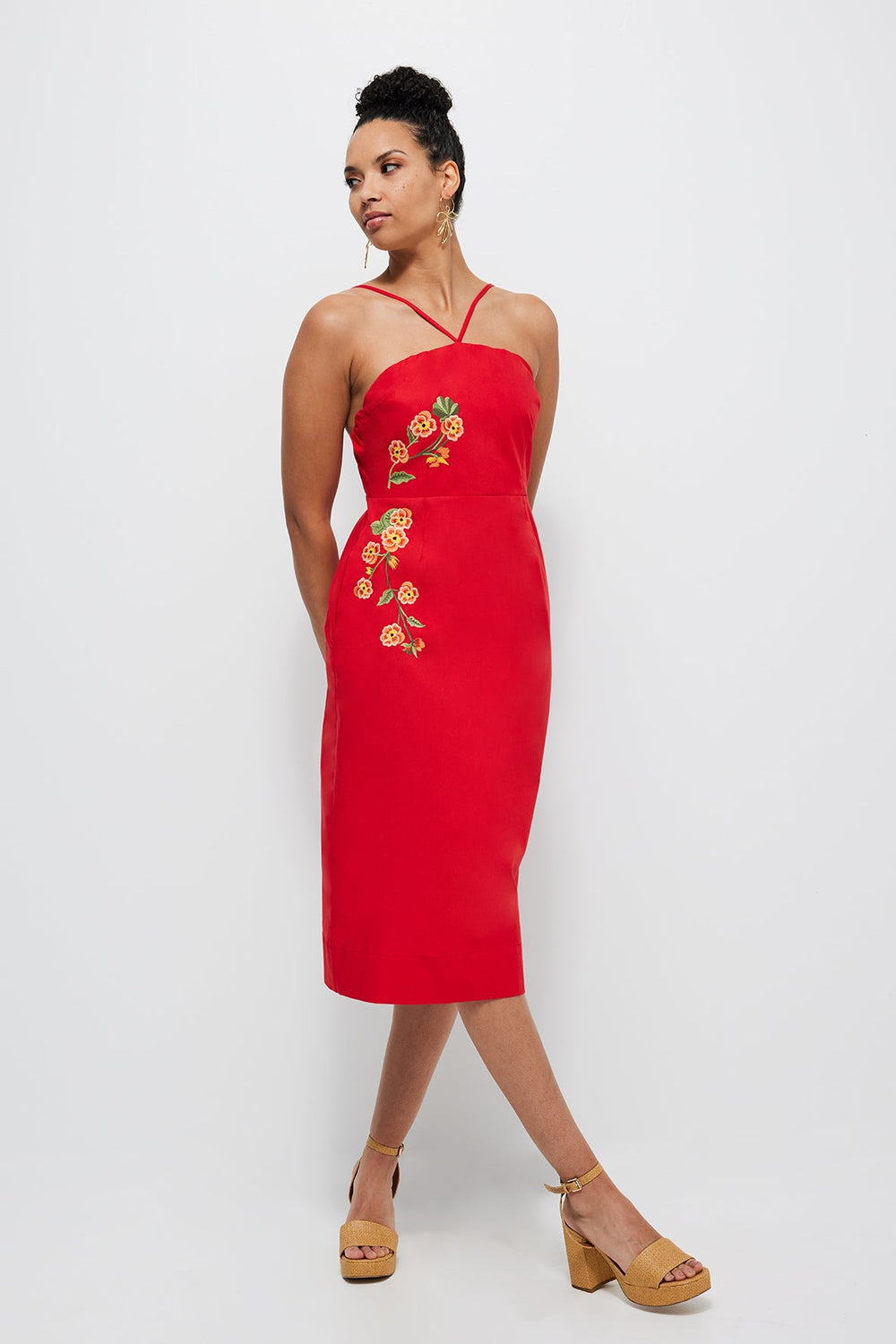 Three-quarter front of Pierre Dress showing red midi sheath with floral embroidery and crossover straps