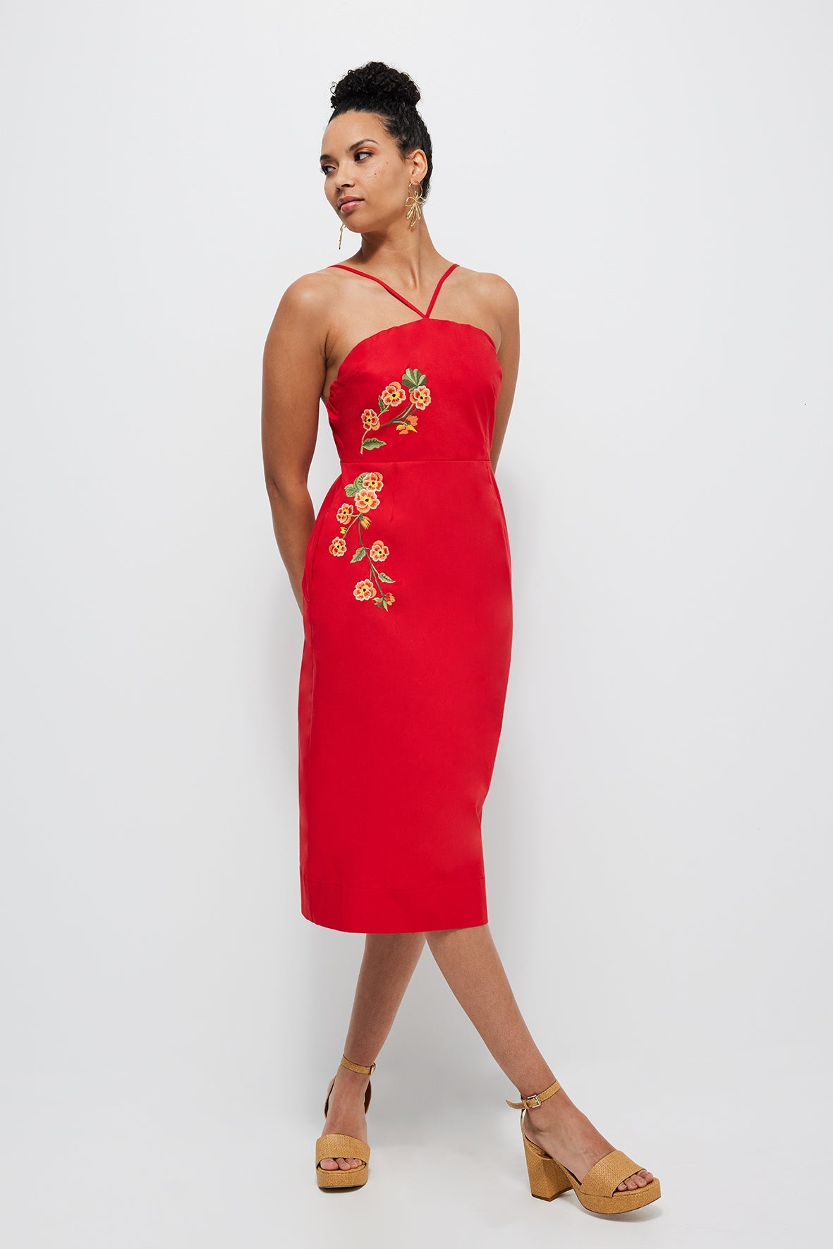 Three-quarter front of Pierre Dress showing red midi sheath with floral embroidery and crossover straps