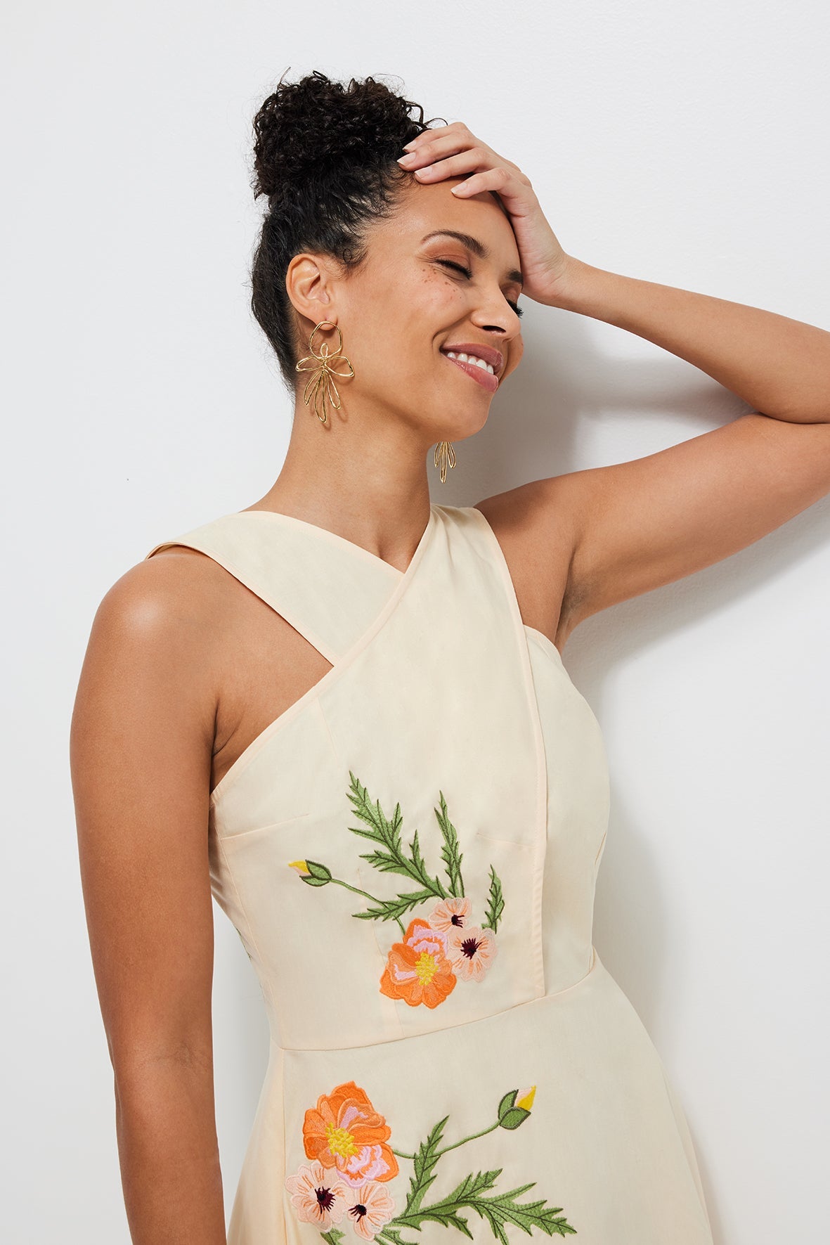 Close-up three quarter view of Samie Dress in light yellow showing cross-shoulder neckline and orange floral embroidery on a white background