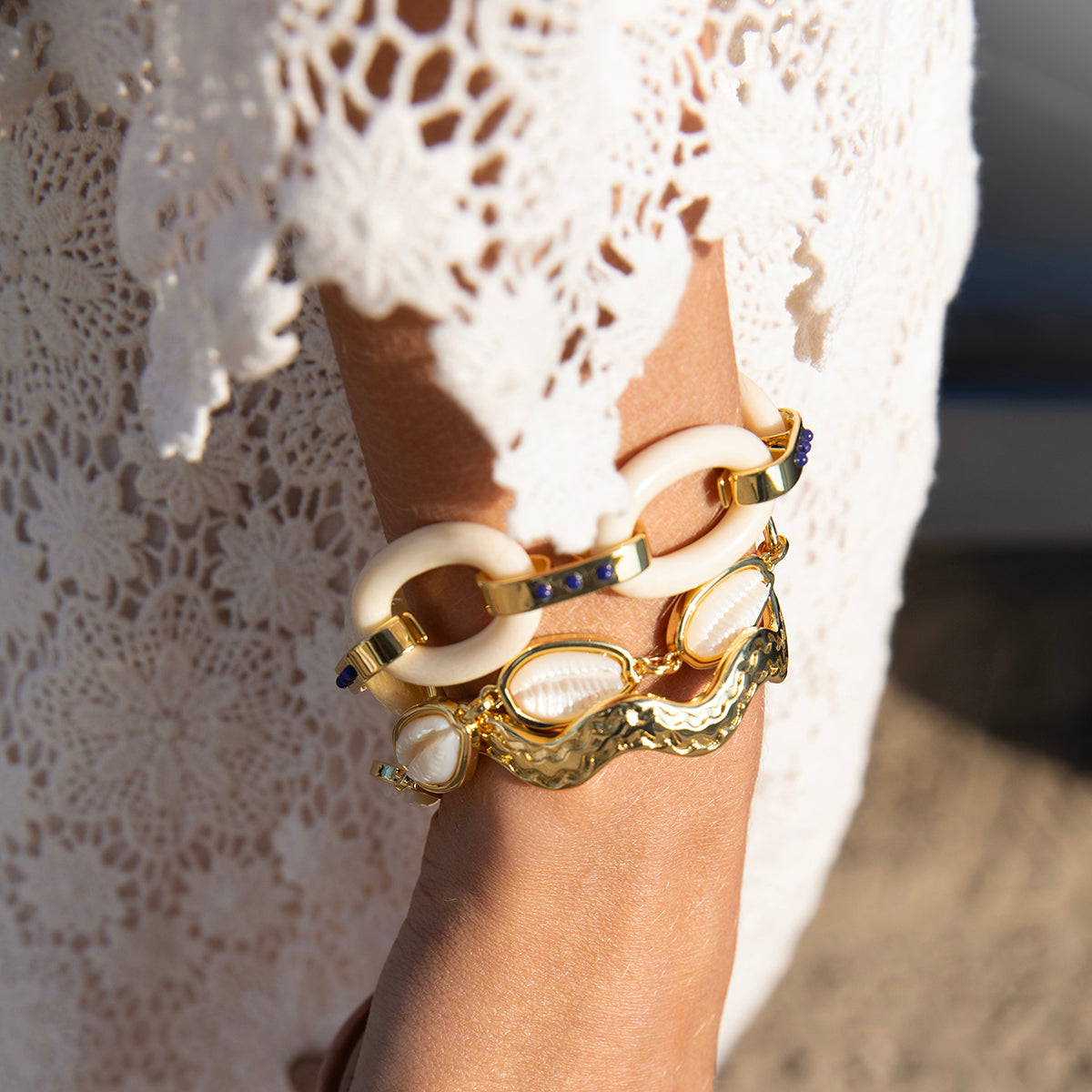 Close-up of Puka Shell Bracelet showcasing mother-of-pearl cowrie shells with 14K gold-dipped details on a wrist