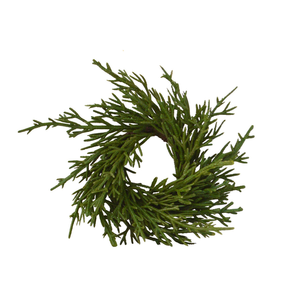 Top view of a faux fir napkin ring showing green artificial branches on a white background